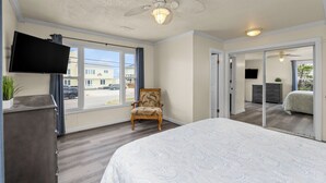 Une chambre à coucher avec un grand lit, une chaise, un téléviseur et un ventilateur de plafond.