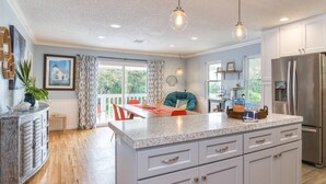 A modern kitchen with a central island, white cabinets, and a stainless steel refrigerator. - Casa Ola (St. Augustine)