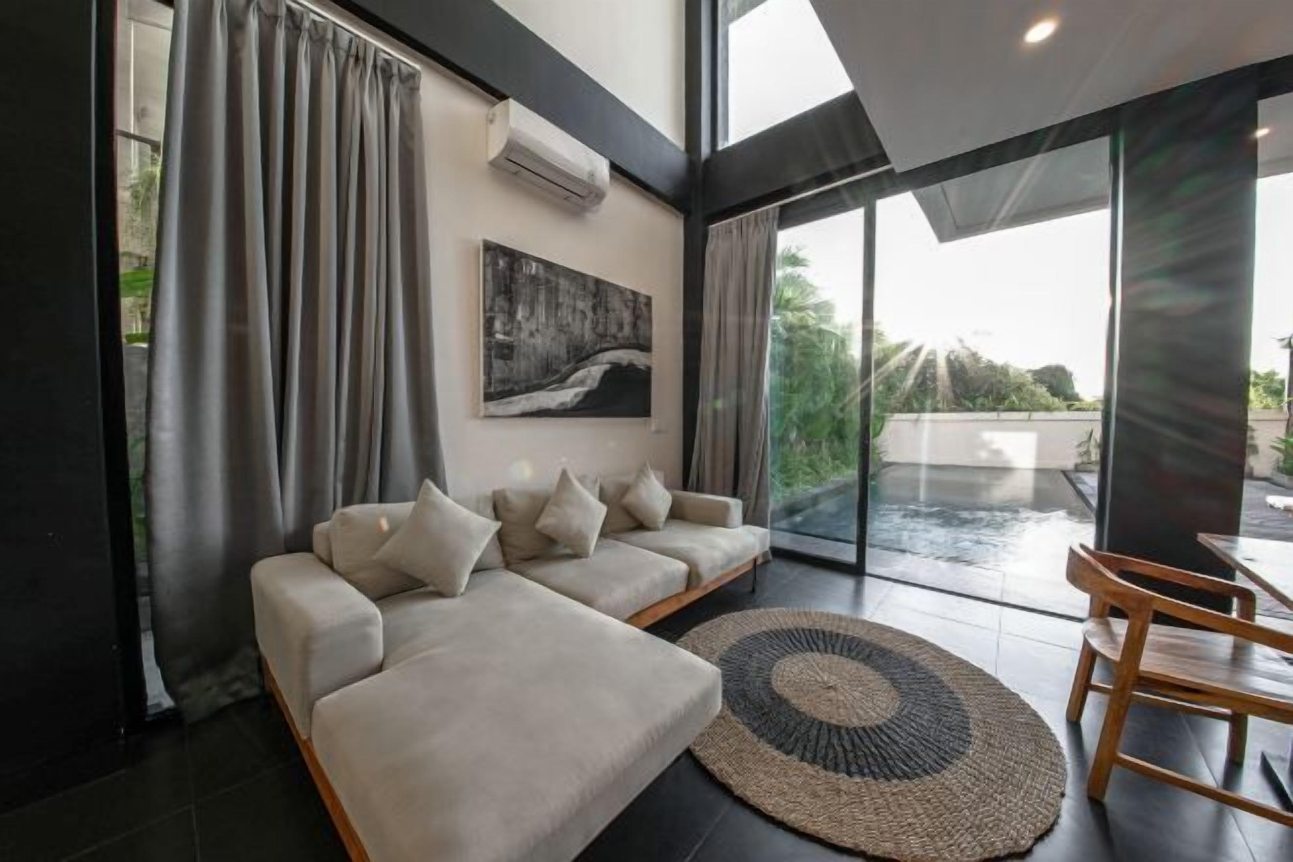 Un salon moderne avec un canapé, un tapis et un tableau accroché au mur.