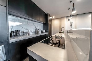 Una cocina moderna con armarios oscuros, salpicadero de mármol y una isla central con asientos.
