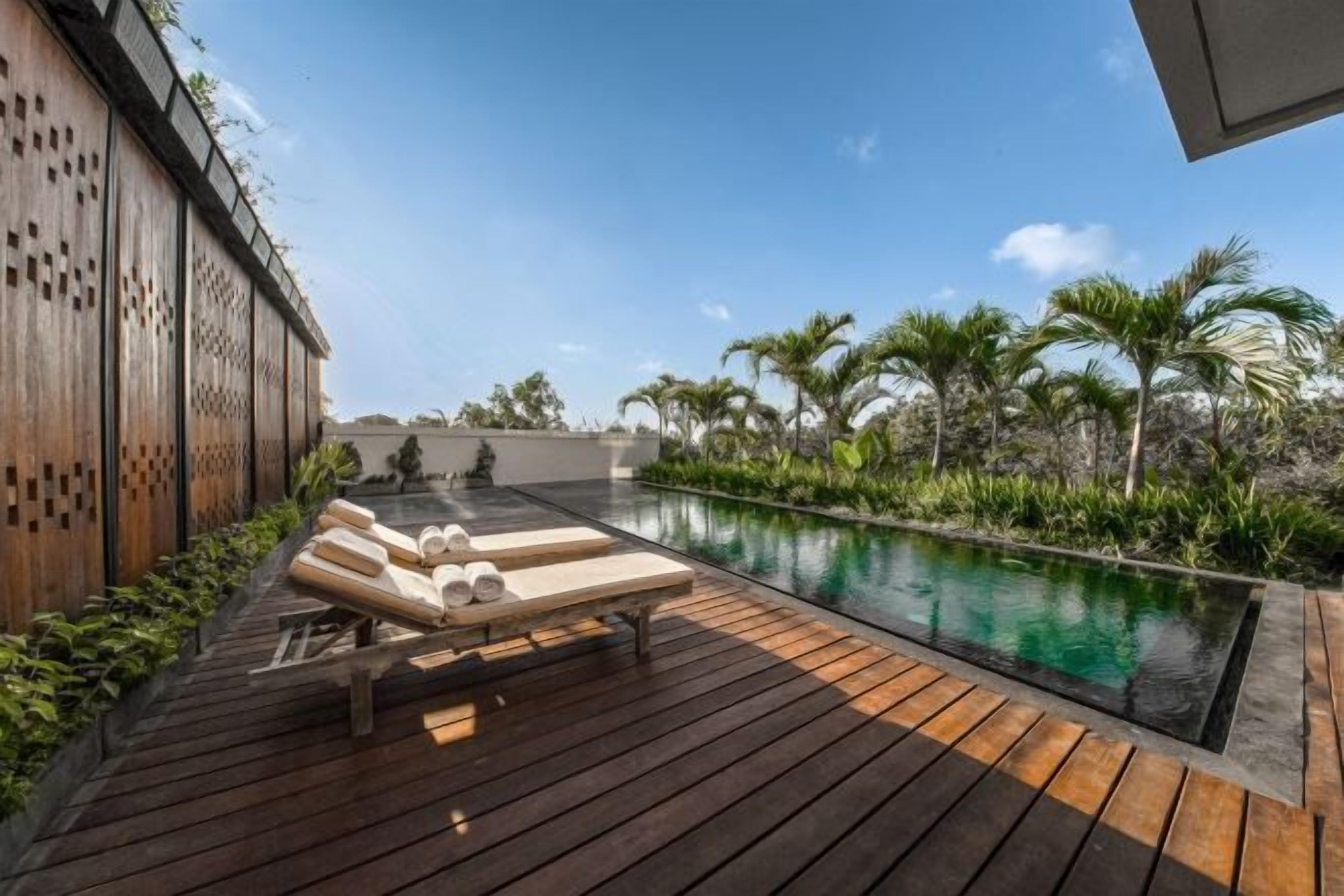 A wooden deck with lounge chairs and a swimming pool.