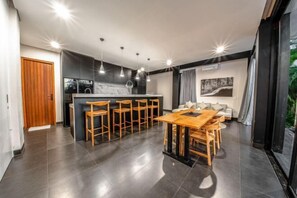 A modern kitchen with a central island, bar stools, and a dining table. - Balangan Beach Villa Freya (Bali)