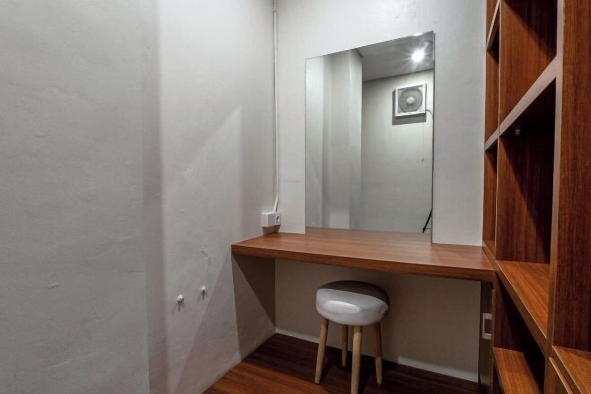 A bathroom with a wooden vanity, a white sink, and a mirror.