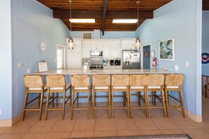 A kitchen with a central island, bar stools, and a clock on the wall. - Hebb Tide- 5 Bd. Semi OF- Direct Bch Access, Pool, Dog Friendly (Virginia Beach)