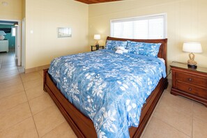 A bedroom with a bed, bedside tables, and a window.