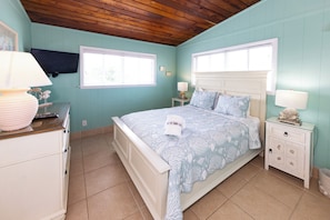 A bedroom with a bed, nightstands, a dresser, and a television.