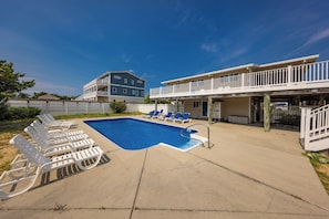 A swimming pool with lounge chairs, a covered deck area, and a two-story building with a balcony. - Hebb Tide- 5 Bd. Semi OF- Direct Bch Access, Pool, Dog Friendly (Virginia Beach)