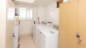 A laundry room with a washing machine, dryer, and a wooden cabinet. - Hebb Tide- 5 Bd. Semi OF- Direct Bch Access, Pool, Dog Friendly (Virginia Beach)