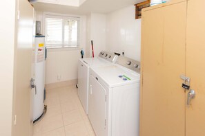 A laundry room with a washing machine, dryer, and a wooden cabinet.
