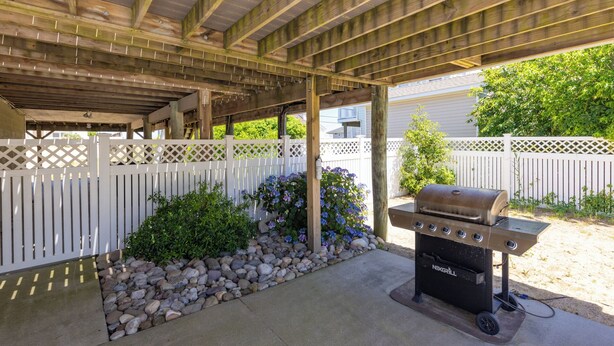 An outdoor patio area with a grill, a wooden pergola, and a white fence. - Hebb Tide- 5 Bd. Semi OF- Direct Bch Access, Pool, Dog Friendly (Virginia Beach)