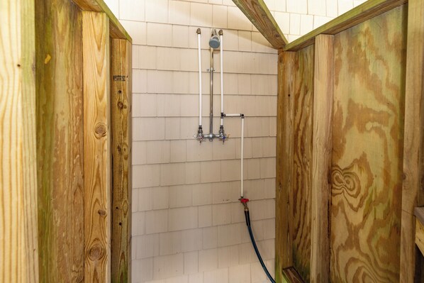 Ducha de madera con cabezal, dos grifos y una manguera.