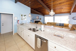A kitchen with a marble countertop, stainless steel sink, and a built-in dishwasher.