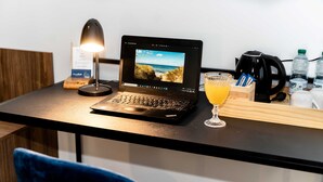 A laptop on a desk with a lamp, a glass of orange juice, a coffee maker, and water bottles. - Sleep Port (Gdańsk)