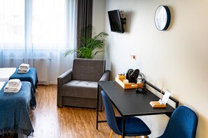 A hotel room with two beds, a sofa, a table with a tray, a TV, and a plant. - Sleep Port (Gdańsk)