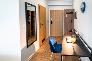 A small room with a desk, chair, and a mirror. There is a door with a sign on it, and a wall clock. - Sleep Port (Gdańsk)