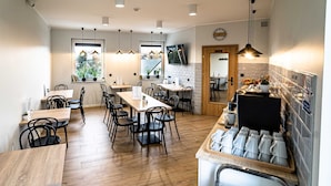 A modern kitchen with wooden flooring, black chairs, and a coffee station. - Sleep Port (Gdańsk)