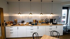 A modern kitchen with white cabinets, a wooden countertop, and four pendant lights.