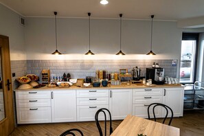 A modern kitchen with white cabinets, a wooden countertop, and four pendant lights. - Sleep Port (Gdańsk)