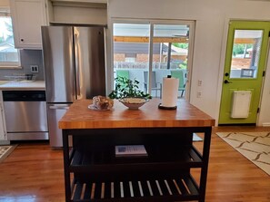 A kitchen with a wooden table, a stainless steel refrigerator, and a green door. - 7 bedrooms, 8 beds and 4 bathroom family house in Denver. (Denver)