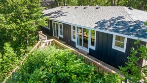 Une maison à l’extérieur sombre, dotée d’un porche abrité et d’un escalier menant à une terrasse.