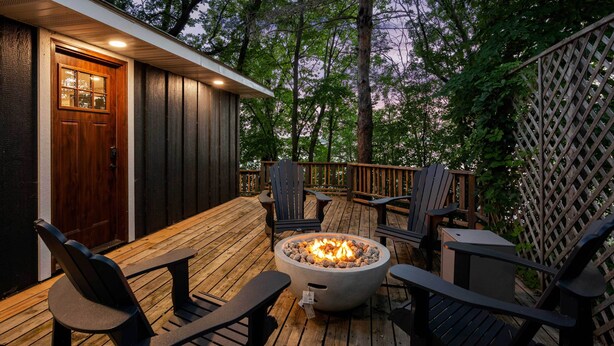 Une terrasse avec un foyer extérieur, des sièges et une porte en bois.