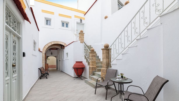 A narrow courtyard with a stone staircase, a red barbecue, and outdoor seating. - Casa Traditionale (Rhodes)