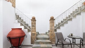 A staircase with stone balustrades, a red pot, and two chairs and a table. - Casa Traditionale (Rhodes)