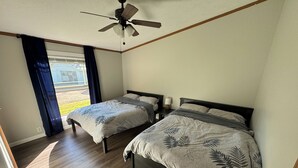 A bedroom with two beds, a ceiling fan, and a window with curtains. - Revilo Timber Haven Mauston - Near The Dells and Castle Rock Lake! (Mauston)