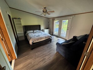 A bedroom with a bed, a ceiling fan, a nightstand, a dresser, and a sliding glass door leading to a balcony. - Revilo Timber Haven Mauston - Near The Dells and Castle Rock Lake! (Mauston)