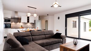 Una sala moderna con un sofá modular, una mesa de centro de madera e iluminación colgante.