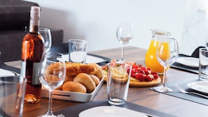 Desayuno con pan, fruta y bebidas sobre una mesa de madera.