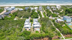 An aerial view of a coastal residential area with houses, a beach, and a clear view of the ocean. - Crescent Cove (St. Augustine)