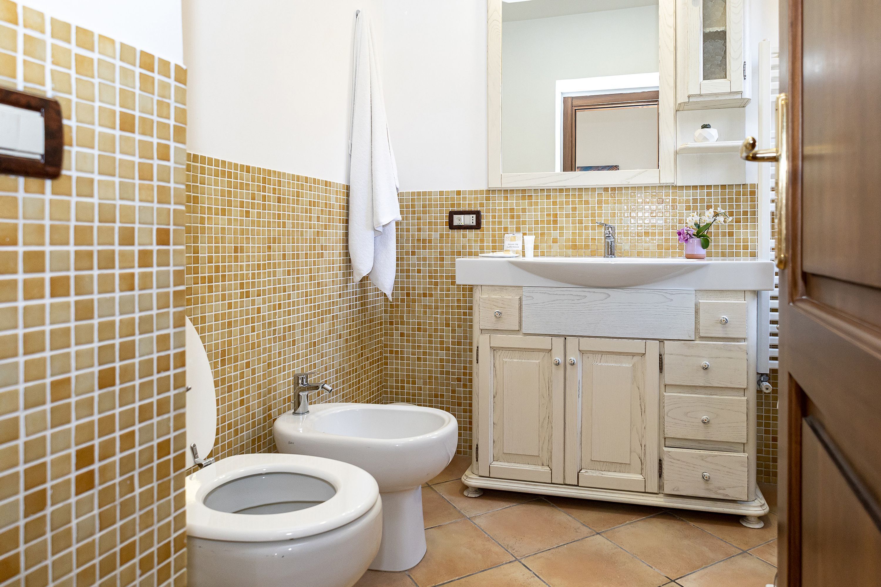 A bathroom with a toilet, bidet, and a sink with a mirror above.