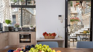 A kitchen with a dining area, a fruit bowl on the table, and a view of the outside balcony.