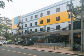 Un hotel de varios pisos con un acceso cubierto y una escalera contra incendios.