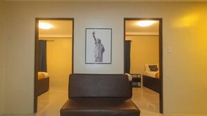 Ein Hotelzimmer mit einem großen gerahmten Bild der Freiheitsstatue, einer braunen Ledersofa und einem Bett mit weißem Kopfteil.