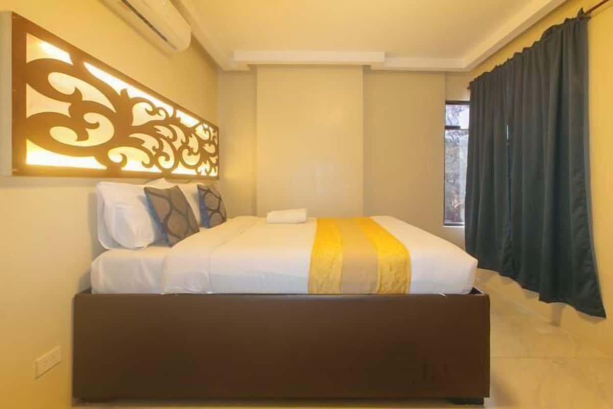 Ein Schlafzimmer mit einem Bett, einer Zierwandverkleidung und einem Fenster mit Vorhängen.