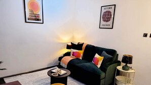 Una sala de estar moderna con un sofá, una mesa de centro y una lámpara. Hay dos cuadros en la pared.