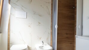 A modern bathroom with a marble wall, wooden floor, a shower, and two toilets. - B&B Sila in Fiore (San Giovanni in Fiore)