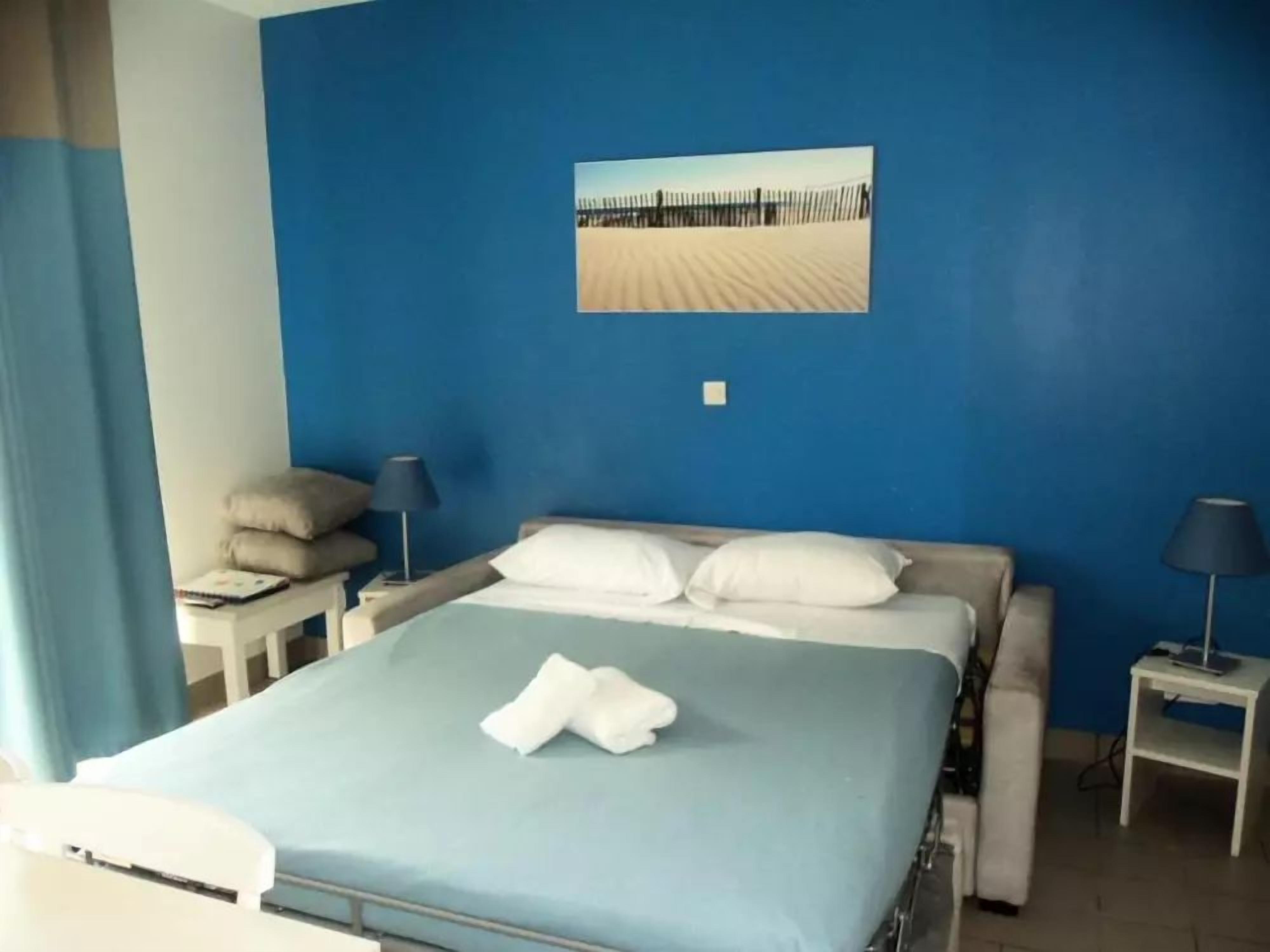 Une chambre d’hôtel avec un lit, une table de chevet, une lampe et un tableau accroché au mur.