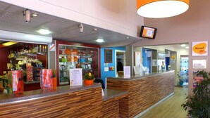 A reception area with a wooden reception desk, a TV mounted on the wall, and a sign indicating the reception area. - Vvf Villages Piriac Sur Mer (Piriac-sur-Mer)