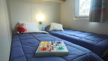 Een slaapkamer met twee bedden, een spel op de vloer en een nachtlampje aan de muur.