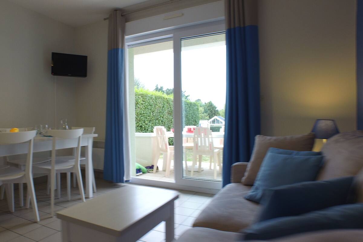 A compact living space with a dining area, a sofa, and a TV mounted on the wall.