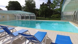 A swimming pool with clear blue water, surrounded by lounge chairs and a covered area. - Vvf Villages Piriac Sur Mer (Piriac-sur-Mer)