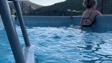 Una persona en una piscina con vistas a colinas al fondo.