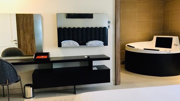 Una camera d'albergo moderna con un letto, una scrivania con un computer, un'area salotto e un bagno.