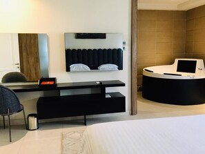 A modern hotel room with a bed, a desk with a computer, a seating area, and a bathroom. - T E L E By Summerset Continental Hotel Maitama (Abuja)
