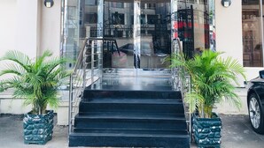 Ingresso di un hotel con portico, vetrate e una scala che conduce all'interno.