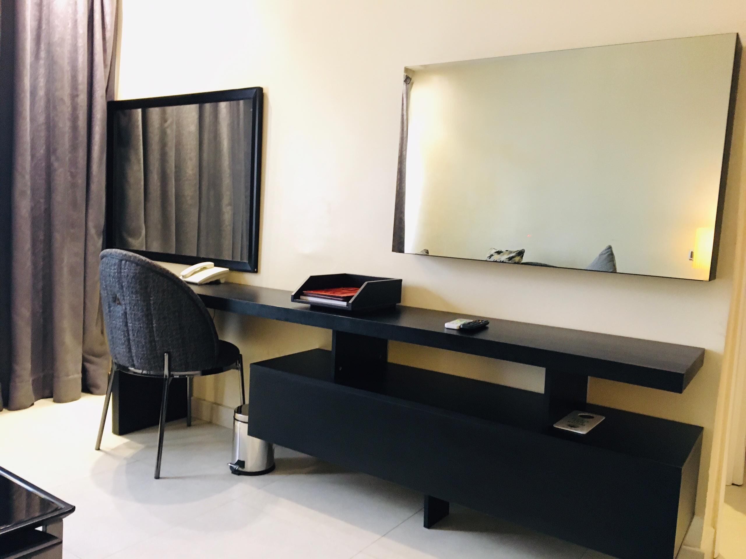 A modern hotel room with a desk, chair, and a large mirror.