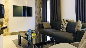 Un soggiorno moderno con un divano, un tavolino in vetro e una TV a schermo piatto montata a parete.